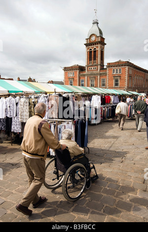 UK Derbyshire Chesterfield Town Center Mann schieben Rollstuhl gebunden Frau durch Marktplatz Stockfoto