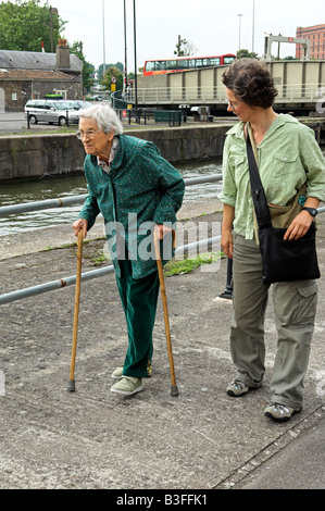 Bestimmt Englisch 92 jährige Seniorin Wandern mit zwei Stöcken mit mittlere gealterte Tochter entlang Bristol Stadt-docks Stockfoto