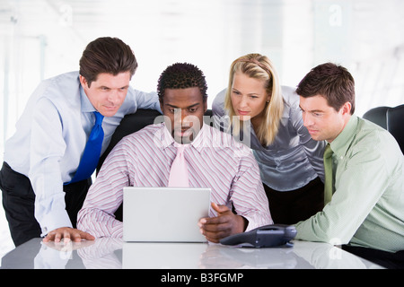 Vier Unternehmer in einem Sitzungssaal Blick auf laptop Stockfoto