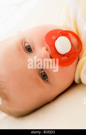 Baby liegend im Innenbereich mit Schnuller Stockfoto