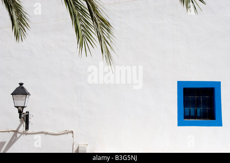 Ibiza, Spanien -16 Aug 2008- kleines blau bemaltes Fenster und eine Straßenlampe an einer weißen Wand Stockfoto