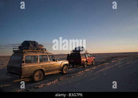 Jeeps bei Sonnenaufgang in dem Salzsee Salar de Uyuni in Bolivien. Stockfoto