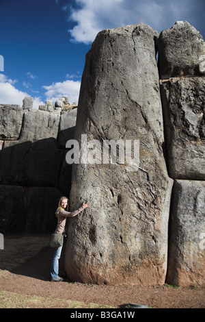 Ein Tourist umarmt einen riesigen Stein in der Inka-Mauern von Sacsayhuaman, etwas außerhalb von Cusco, Peru. Stockfoto