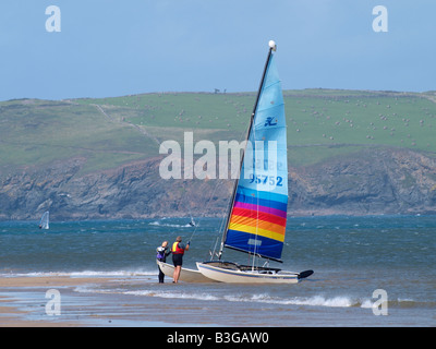 Paar mit einem Katamaran gestrandet am Strand von Padstow, Cornwall, UK Stockfoto