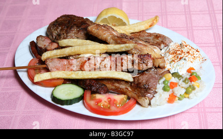 Einem griechischen Tavernen Grillteller Souvlaki Döner Spieß Lamm Koteletts Bauch Schweinekotelett Joghurt Reis und Pommes Frites mit Salat Stockfoto