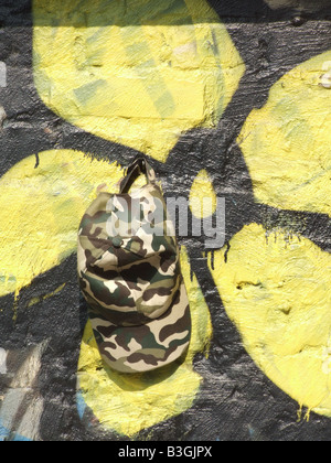 Army Cap und gelbe Blume Graffiti an der Wand Stockfoto