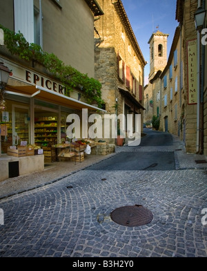 die gepflasterten Straßen von Châteauneuf-du-Pape mit der Epicerie (Lebensmittelgeschäft) und der Kirchturm im Hintergrund Stockfoto