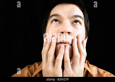 Porträt von asiatischen jungen Mann mit den Händen auf Gesicht blickte Stockfoto