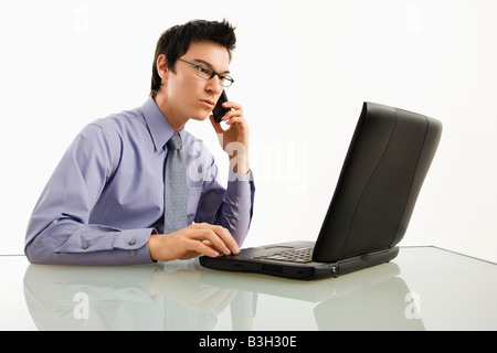 Asiatische Geschäftsmann am Schreibtisch arbeiten am Laptop, am Handy sprechen Stockfoto
