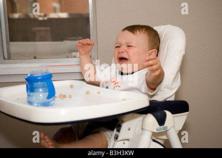 acht Monate altes Baby junge weinend in seinem Hochstuhl zu Hause Stockfoto