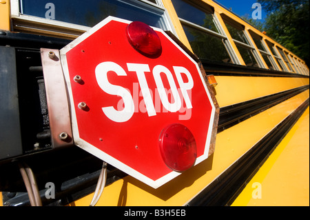 Das große rote Stoppschild signalisieren Arm an der Seite einen gelben Schulbus Autofahrer von Studenten zu warnen. Stockfoto