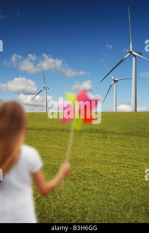 Mädchen mit Windmühle vor Windturbinen Stockfoto