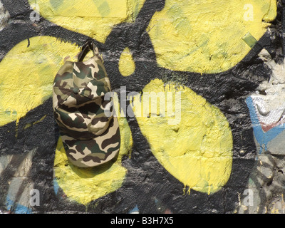 Army Cap und gelbe Blume Graffiti an der Wand Stockfoto