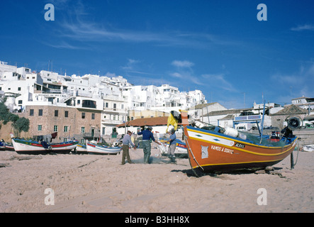 Fischer sind in der Regel ihre Netze rund um ihre Boote am Strand in der weiß getünchten Angeln Stadt Albufeira Stockfoto