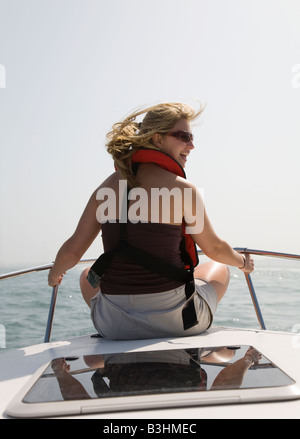 Eine junge Frau sitzt auf der Vorderseite eines Schiffes auf hoher See. Tragen einen Rettungsring. Stockfoto