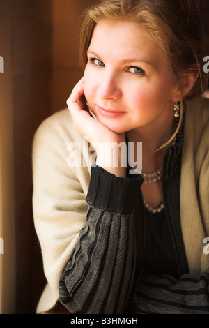 Blonde Frau neben einem natürlichen Licht Fenster am Anfang des Winters flachen Depth of Field Stockfoto