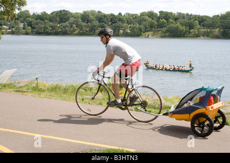 Vater hausieren Fahrrad mit Kindern im Wagen und Drachen Boot auf See. Drachen-Festival Lake Phalen Park St. Paul Minnesota USA Stockfoto