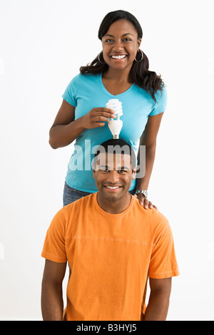 African American Frauen energiesparende Glühbirne über Mann s Kopf halten Stockfoto