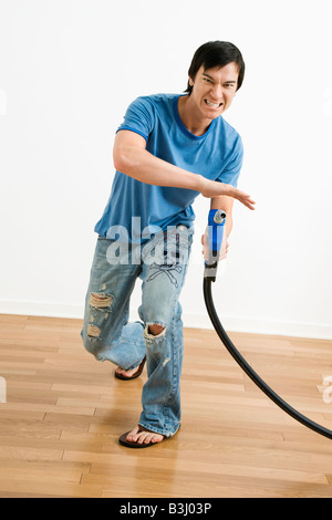 Asiatische junge Mann mit dem Ziel Benzin Pumpe Düse wie eine Waffe Stockfoto