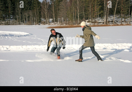 Junge Paare, die Spaß im Schnee spielen Stockfoto