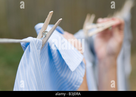 Nahaufnahme von einer jungen Frau Hände hängende Kleidung zum Trocknen auf einer Linie Stockfoto