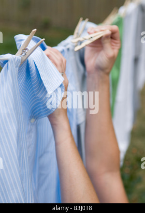 Nahaufnahme von einer jungen Frau Hände hängende Kleidung zum Trocknen auf einer Linie Stockfoto