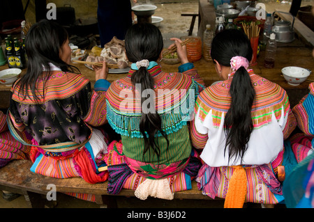 Hmong Blumenmädchen beim Mittagessen an einem Marktstand in Bac Ha Markt Nord-Vietnam Stockfoto