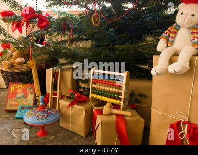 Eine Auswahl von altmodischen Kinderweihnacht präsentiert darunter, die einen Weihnachtsbaum im viktorianischen Stil dekoriert Stockfoto