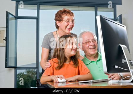 Großeltern und Enkeltochter mit Computer zu Hause Stockfoto