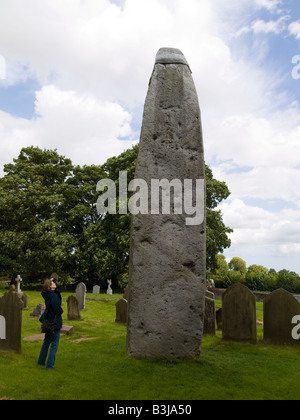 Eine Frau schaut den alten Monolith 7 6 Meter hoch das höchste Gebäude im Vereinigten Königreich auf dem Kirchhof am Rudston East Yorkshire Stockfoto