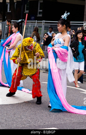 Notting Hill Carnival Parade, Beijing Olympic Group, zwei ziemlich Teenager mit Luftschlangen & Tiger Figur führen in Straße Stockfoto