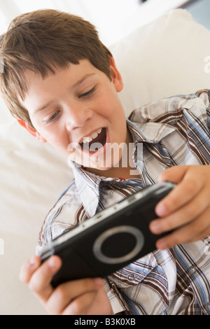 Junge mit Handheld-Spiel im Innenbereich Stockfoto