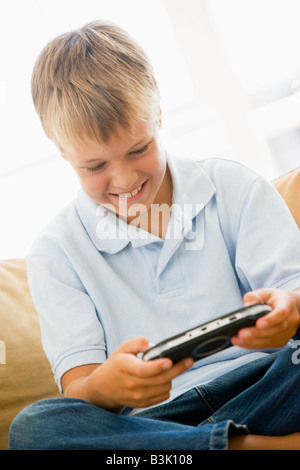 Kleiner Junge im Wohnzimmer mit handheld Videospiel lächelnd Stockfoto