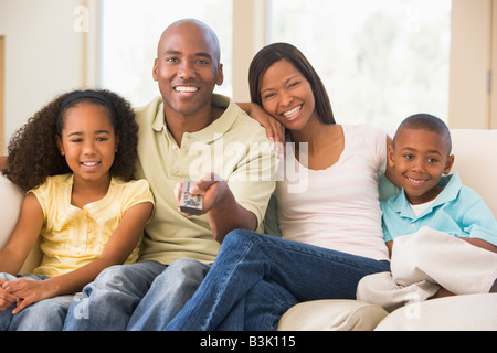 Familie sitzen im Wohnzimmer mit Fernbedienung lächelnd Stockfoto