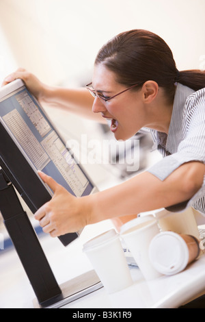 Frau im Computerraum packte ihren Monitor und schreien Stockfoto