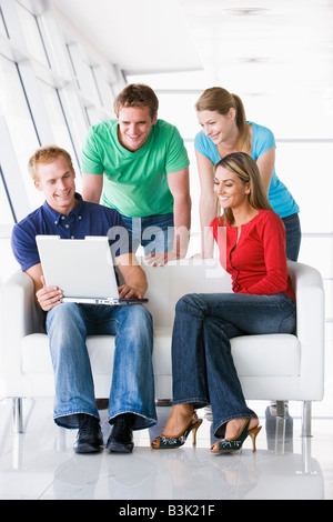 Vier Menschen in Lobby Blick auf Laptop lächelnd Stockfoto