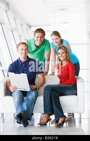 Vier Personen in der Lobby mit Laptop lächelnd Stockfoto