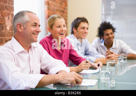 Vier Unternehmer im Sitzungssaal lächelnd Stockfoto