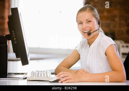 Geschäftsfrau, die Kopfhörer sitzen im Büro Lächeln auf den Lippen tragen Stockfoto