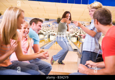 Familie in der Bowlingbahn mit zwei Freunden jubeln und lachen Stockfoto