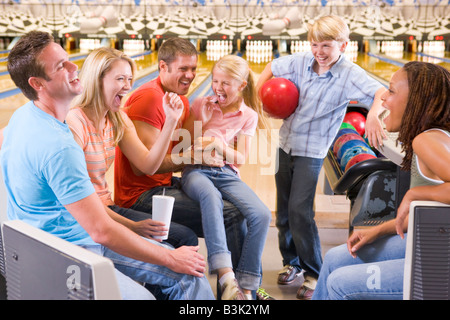 Familie in der Bowlingbahn mit zwei Freunden jubeln und lachen Stockfoto