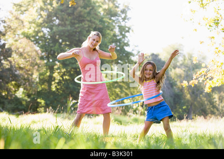 Frau und junge Mädchen im Freien mit Hula Hoops und lächelnd Stockfoto