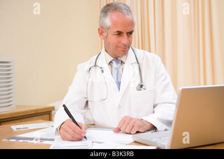 Arzt mit Laptop und schreiben in Arztpraxis Stockfoto