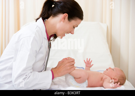 Doctor giving Checkup, Baby in Exam Room lächelnd Stockfoto