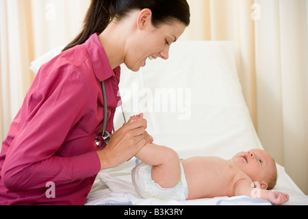 Doctor giving Checkup, Baby in Exam Room lächelnd Stockfoto