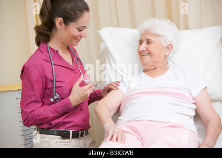 Arzt Frau in Exam Room lächelnd Nadel verleihen Stockfoto
