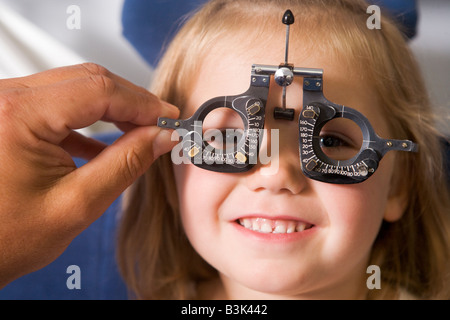 Optiker in Untersuchungszimmer mit jungen Mädchen im Sessel lächelnd Stockfoto