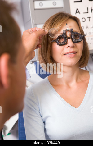 Optiker in Untersuchungszimmer mit Frau auf Stuhl Stockfoto