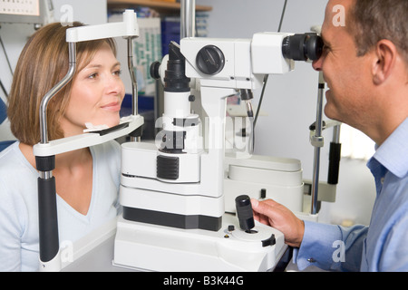 Optiker in Untersuchungszimmer mit Frau auf Stuhl Stockfoto