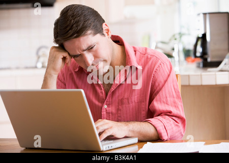Mann in der Küche mit Laptop Stirnrunzeln Stockfoto